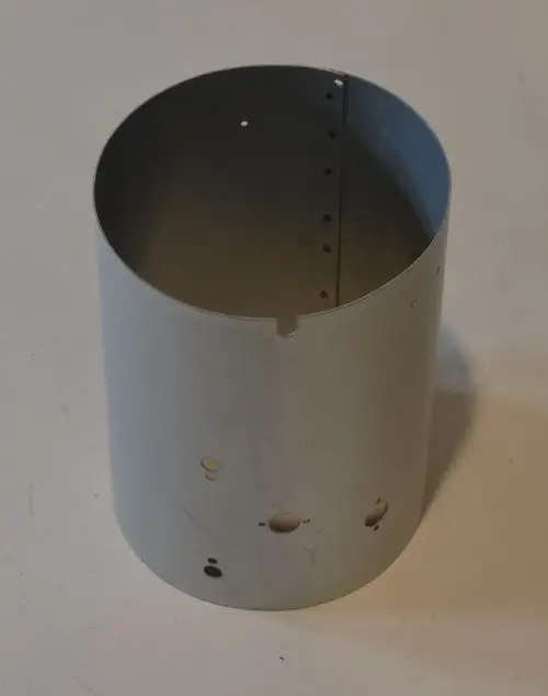 Metallischer Zylinder mit Löchern, vermutlich für eine Heizungsanwendung, möglicherweise ein Innenmantel von Remko. Der Zylinder hat eine gerade Form und eine einseitige Öffnung.