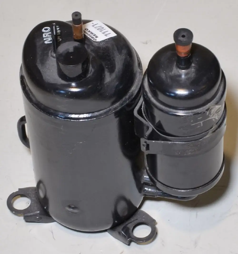 Schwarzer Kompressor mit zwei Kammern, montierbar, ausgestattet mit Rohranschlüssen. Produkt von Remko, für den Einsatz in Klimaanlagen geeignet.