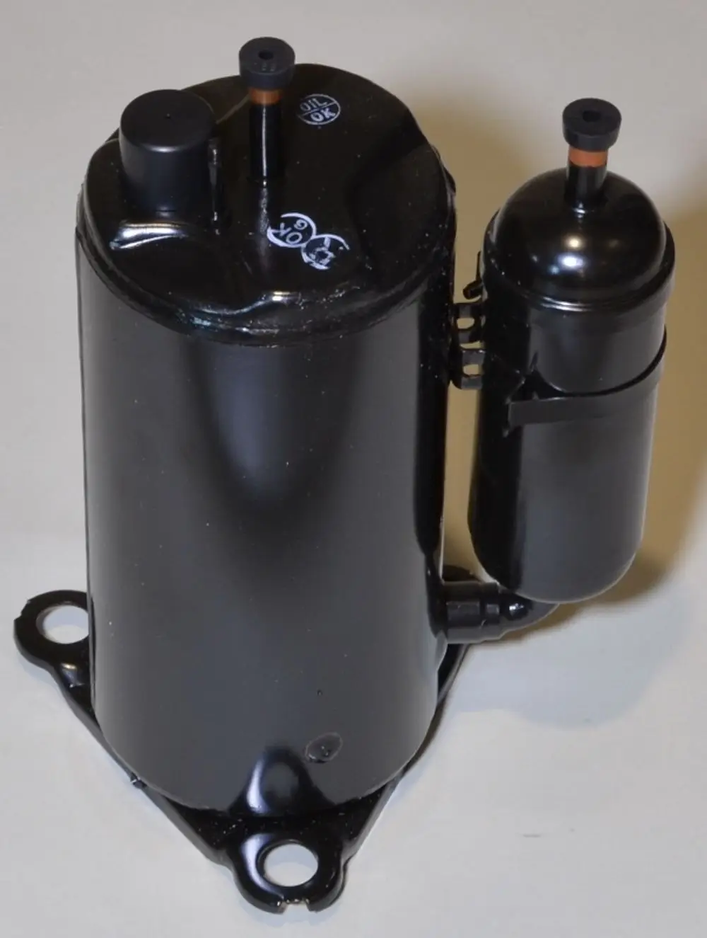 Remko-Kompressor in schwarzer Ausführung, zylindrische Form mit zwei Anschlüssen. Vorne befindet sich ein kleiner Behälter. Montageflächen an der Unterseite erkennbar.