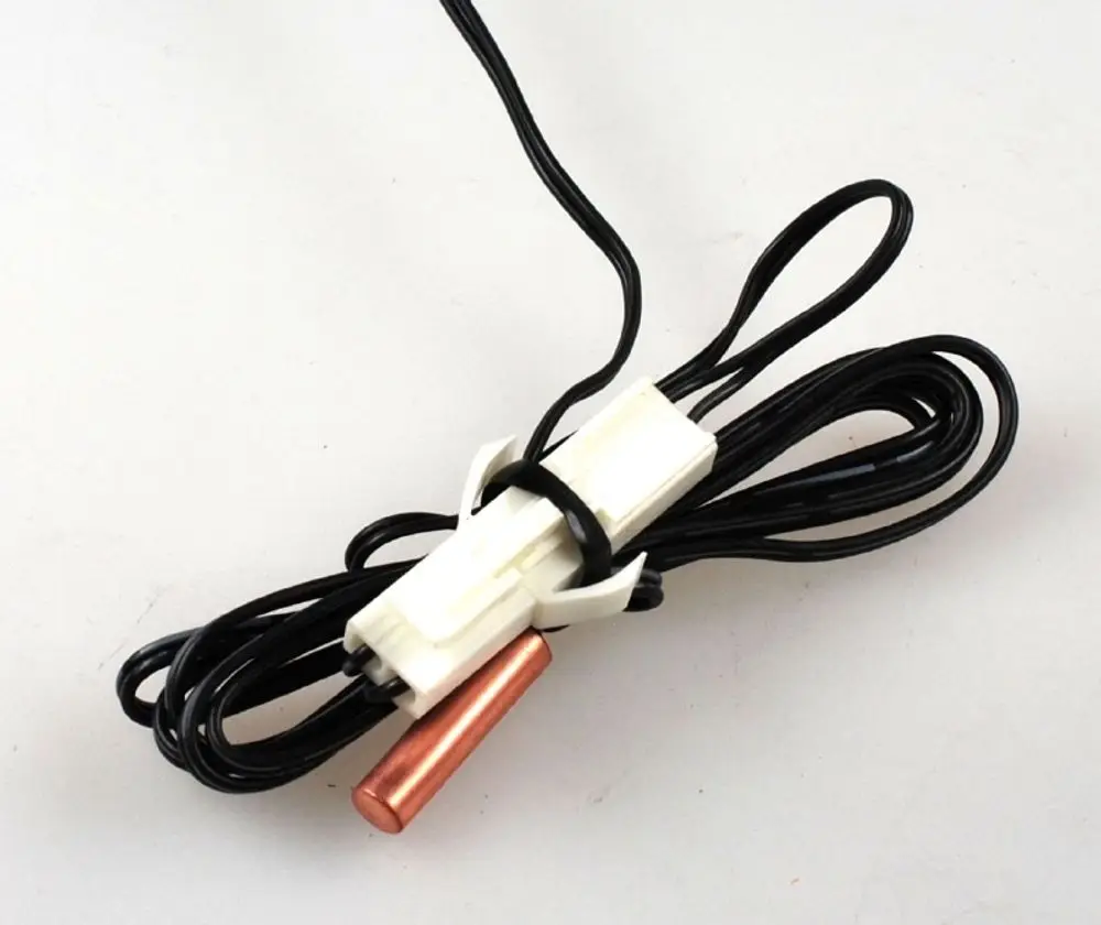 Sensor mit schwarzem Kabel, weißer Halterung und kupferner Spitze, hergestellt von Remko. Ideal für Anwendungen in Lamellentauschern.