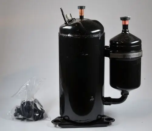 Remko-Kompressor in schwarzer Ausführung, mit zwei Anschlüssen oben, verbunden mit einem kleineren Behälter, daneben ein Plastikbeutel mit Zubehörteilen.