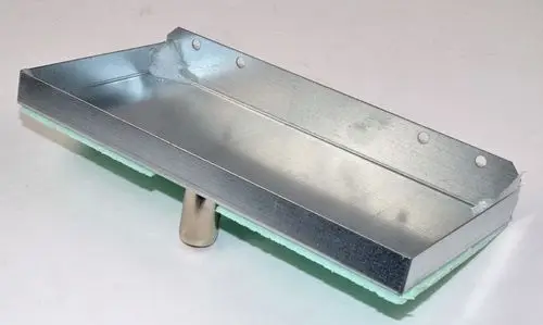 Kondensatwanne aus Metall mit einer grünen Unterlage und einer zentralen Halterung. Sie gehört zur Ventilbaugruppe von Remko und ist für vertikale Anwendungen konzipiert.