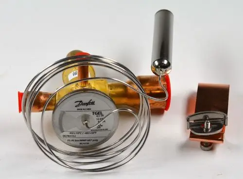 Expansionsventil mit rotem Anschluss und Metallsensor, hergestellt von Remko, umgeben von einer Kupferleitung und einem montierbaren Winkelstück.