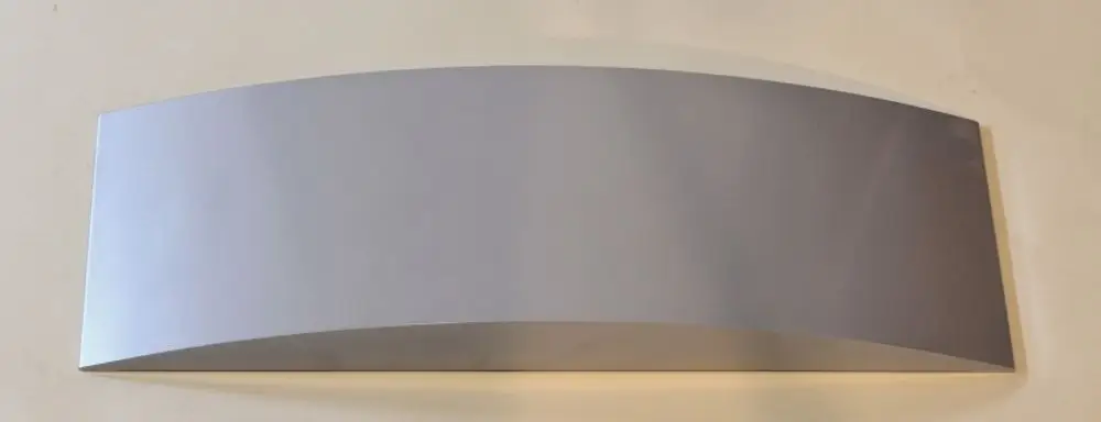 Silbernes, gebogenes Metallblech auf hellem Hintergrund, vermutlich ein Teil von einem Gerät oder einer Installation, möglicherweise von der Marke Remko.
