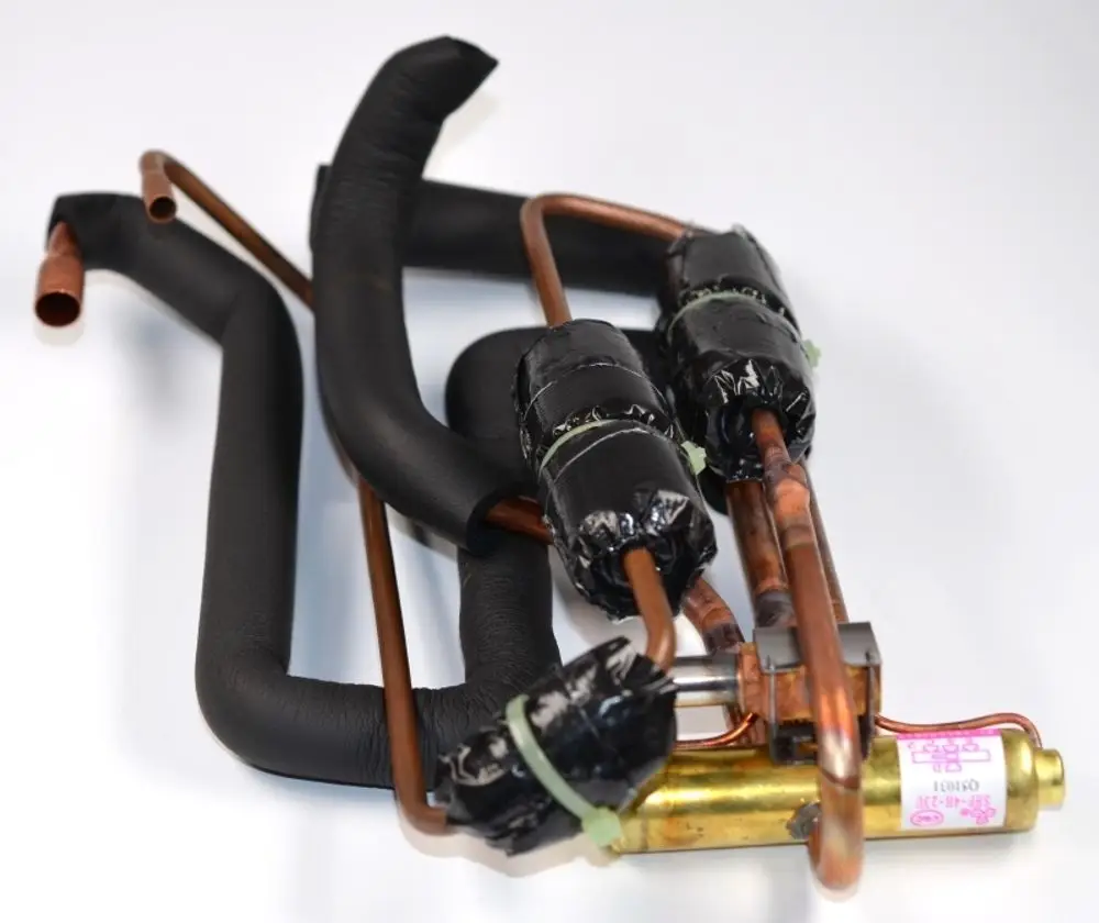 4-Wege-Ventilbaugruppe von Remko mit mehreren Kupferrohren, teilweise isoliert und mit schwarzen Verpackungen, montiert in einem kompakten Layout.