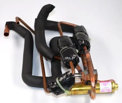 4-Wege-Ventilbaugruppe von Remko mit mehreren Kupferrohren, teilweise isoliert und mit schwarzen Verpackungen, montiert in einem kompakten Layout.