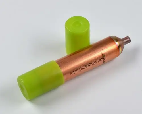 Trockenfilter in Kupferfarbe mit grünem Kunststoffdeckel, hergestellt von Remko. Der Filter hat eine zylindrische Form und einen schmalen Auslass.