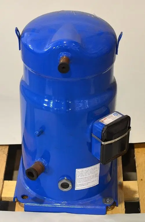 Blauer Kompressor von Remko, zylinderförmig mit zwei Anschlüssen an der Vorderseite und einem Anzeigegerät an der Seite, auf Holzpalette platziert.
