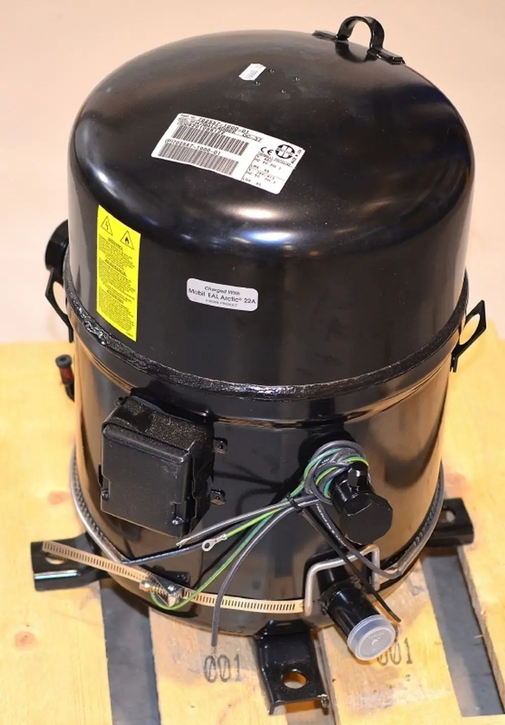 Schwarzer Remko-Kompressor mit elektrischen Anschlüssen und Ventileinheiten, auf Holzpalette präsentiert. Herstellerinformationen und Warnhinweise sichtbar.