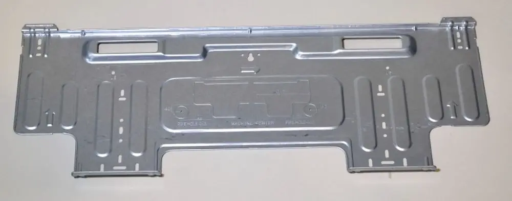Wandhalterung aus Metall in silberner Farbe, möglicherweise von Remko, mit mehreren Aussparungen und Löchern zur Befestigung an Wänden oder anderen Oberflächen.