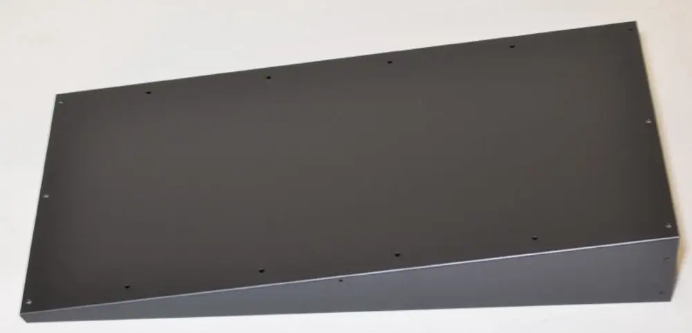 Schwarzes Metallblech mit schräger Kante und mehreren Befestigungslöchern, möglicherweise für den Einsatz in Geräten von Remko.