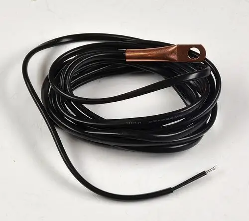 Schwarzes Kabel mit einem copperfarbenen Ringterminal und freiliegenden Drahtenden. Teil einer Sensorinstallation von Remko für die Erkennung von Wasseraustritt.