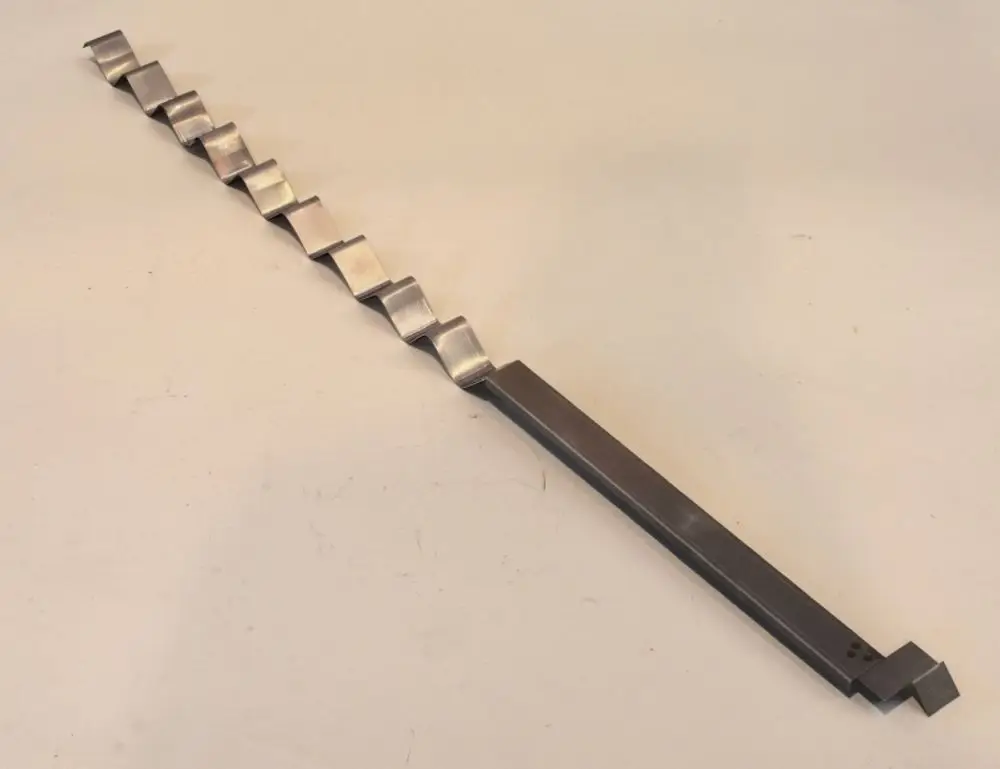 Stangenförmiges Metallgerät mit wellenförmigem Profil, möglicherweise für die Luftzirkulation. Erzeugt von der Marke Remko.
