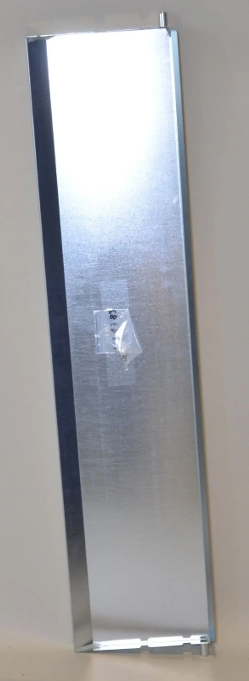 Kondensatwanne aus Metall in schmaler, länglicher Form mit einem Verbindungselement und einer transparenten Tüte mit Befestigungsteilen. Produkt von Remko.
