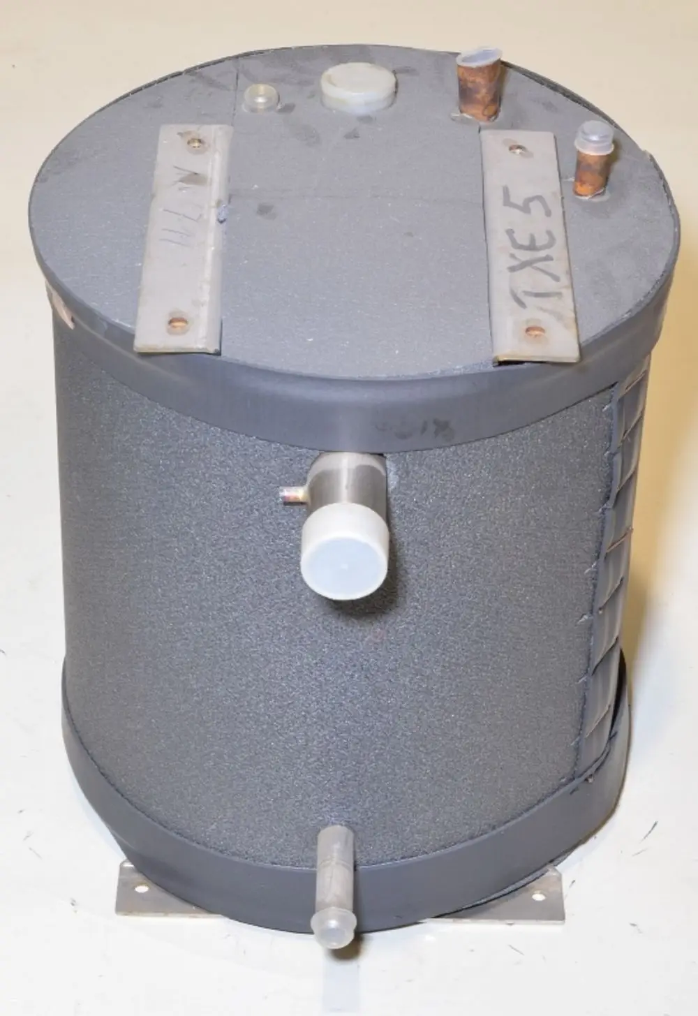 Rohr-in-Rohr-Wärmetauscher von Remko, zylindrische Bauform mit mehreren Anschlüssen, graue Oberfläche und Befestigungslöcher an der Basis.