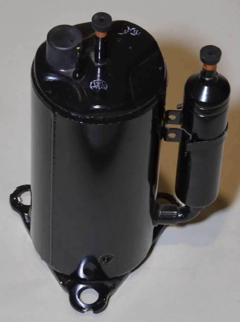 Schwarzer Kompressor von Remko mit zwei Anschlüssen und einer halbrunden Seitenkomponente. Montagebasis mit Bohrungen sichtbar.