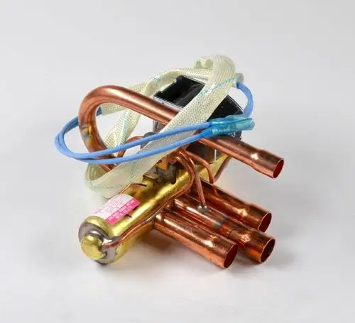 Umkehrventil mit Kupferrohren und elektrischer Spule, gefertigt von Remko. Es sind mehrere Anschlüsse sichtbar.