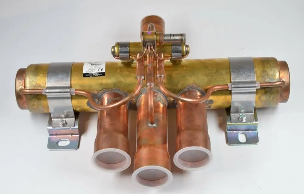 Kupferfarbenes Umkehrventil mit mehreren Anschlüssen, montiert auf einer Metallbasis. Hersteller ist Remko.