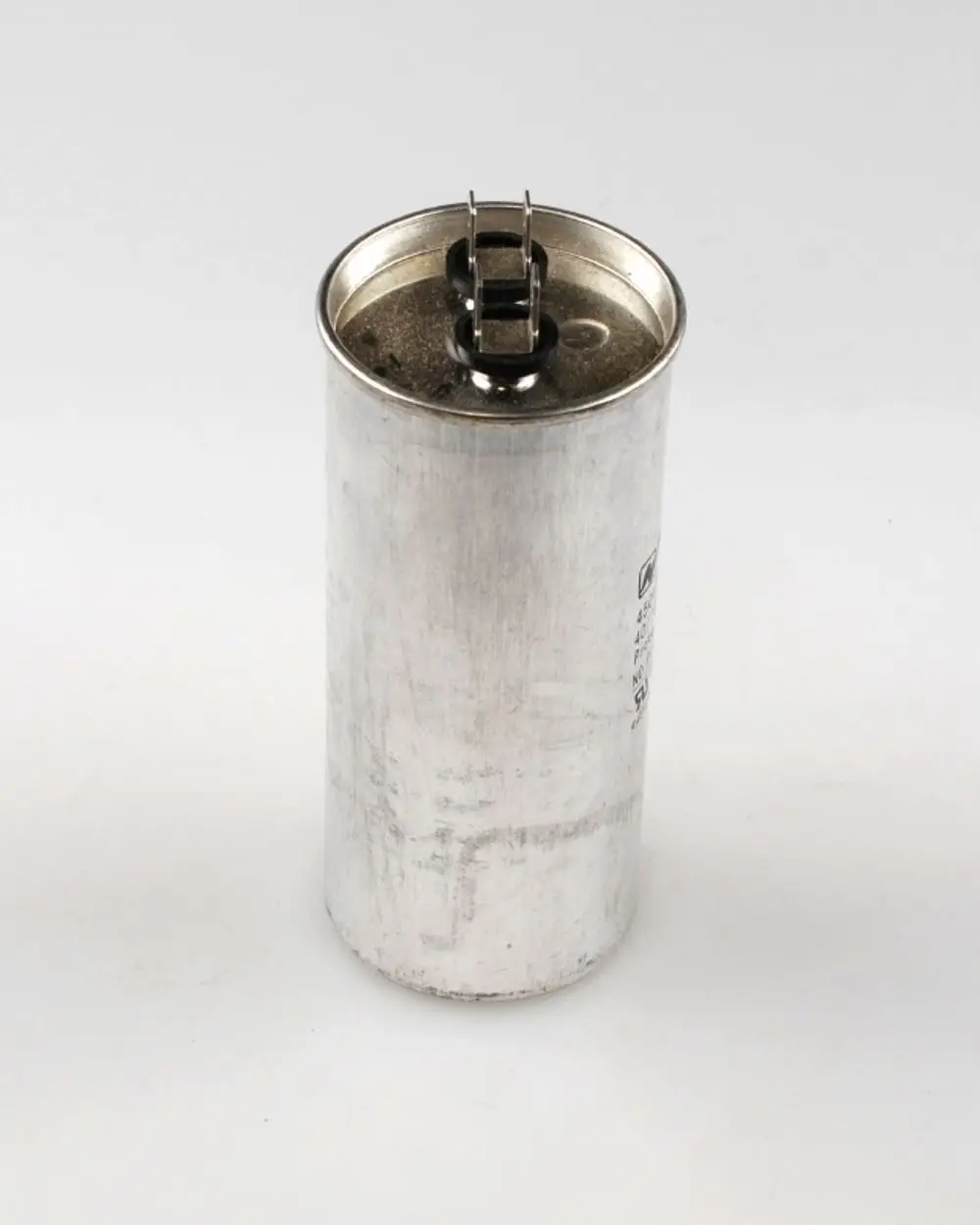 Zylindrischer Metallbehälter mit zwei Anschlüssen oben, der einen Kondensator darstellt. Er stammt von der Marke Remko.