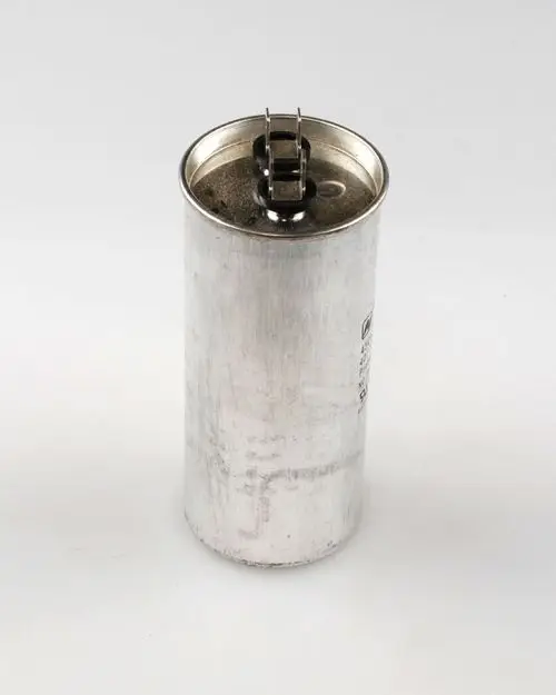 Zylindrischer Metallbehälter mit zwei Anschlüssen oben, der einen Kondensator darstellt. Er stammt von der Marke Remko.