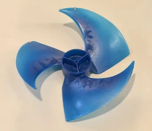 Remko Ventilatorflügel in Blau mit drei gebogenen Klingen und zentralem Befestigungspunkt. Der Flügel ist aus Kunststoff gefertigt und zeigt Gebrauchsspuren.