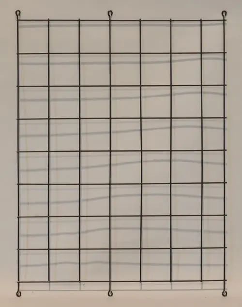 Schwarzes Gitter aus Draht mit gleichmäßiger Unterteilung, geeignet für Verflüssiger, von der Marke Remko, vor heller Wand montiert.