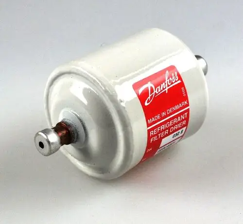 Weißer Trockenfilter mit rotem Etikett und Anschlüssen an beiden Enden, hergestellt von Remko, für den Einsatz in Kühlsystemen zur Entfernung von Feuchtigkeit und Verunreinigungen.