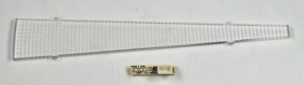 Transparente LED-Beleuchtungskomponente der Marke Remko mit schmaler, dreieckiger Form und einer elektronischen Platine in der Mitte.