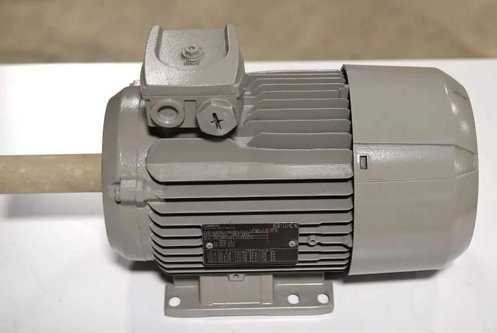 Remko Elektromotor in grauer Ausführung, mit aufrecht montierter Welle und seitlichem Anschluss. Technische Informationen auf der Typenschildfläche sichtbar.
