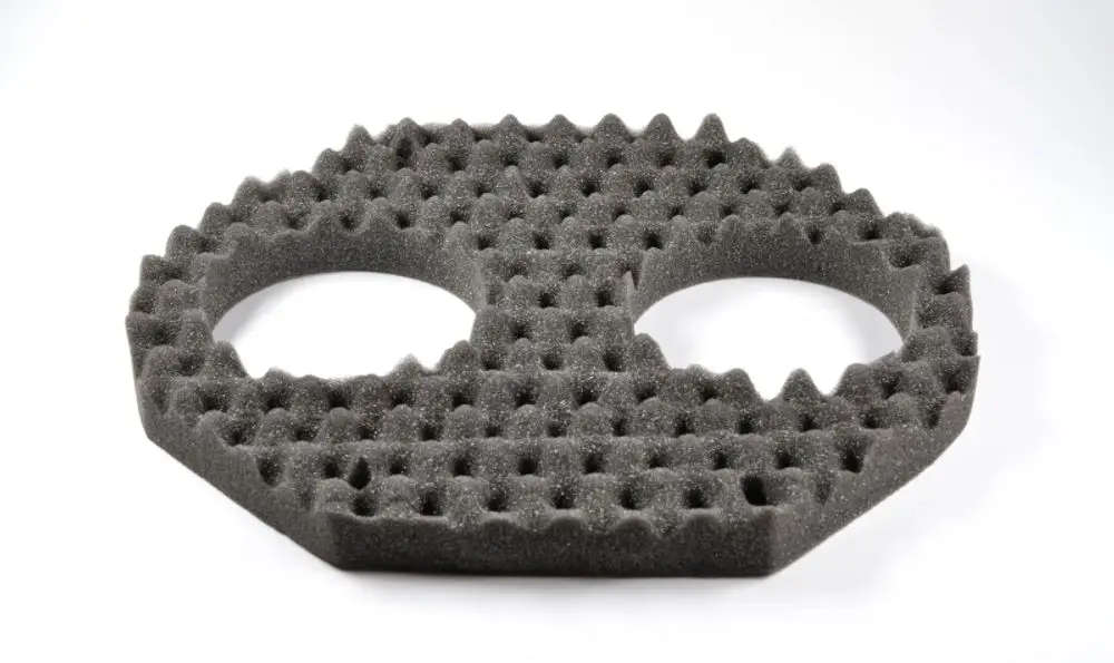 Grauer Schaumstoffring mit zwei runden Öffnungen in der Mitte und strukturierter Oberfläche. Produkt von Remko, geeignet zur Dämmung in technischen Anwendungen.