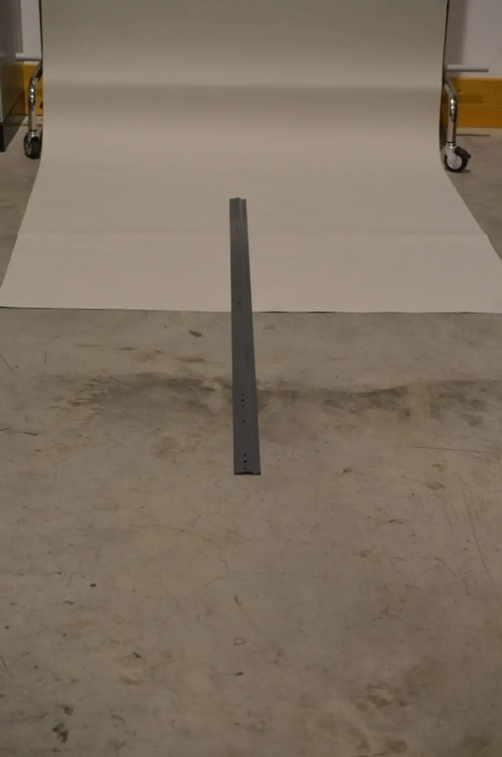 Graue Wandkonsole auf einem Betonboden, mit einer hellen Fotopapierunterlage im Hintergrund. Geeignet für feste Montagen, Marke Remko.