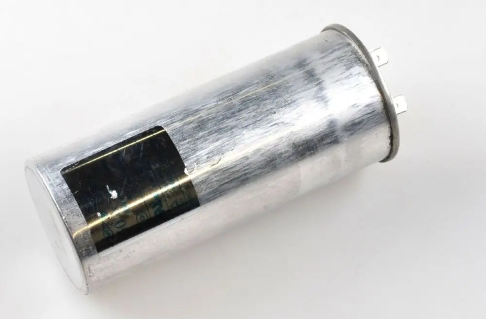 Metallischer Kondensator mit zwei Anschlussklemmen. Die Oberfläche ist glänzend und zeigt leichte Gebrauchsspuren. Hersteller: Remko.