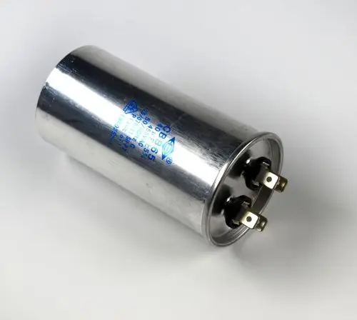 Betriebskondensator mit silberner Metalloberfläche und zwei Anschlussklemmen, Teil eines Geräts von Remko. Schriftzug und technische Angaben auf der Oberseite sichtbar.