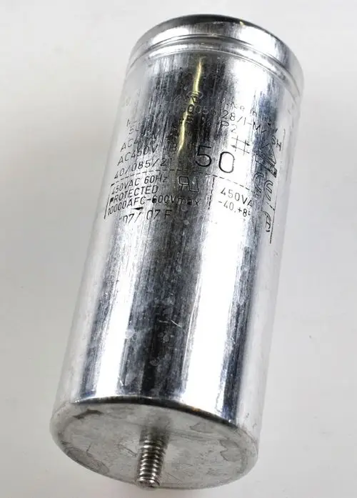 Kondensator von Remko mit metallischer Oberfläche und gravierten technischen Daten. Hervorhebung von Spannungs- und Frequenzeinstellungen. Gewindeverschluss am Boden sichtbar.