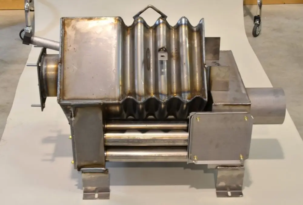 Edelstahl-Brennkammer von Remko mit gewellter Oberfläche und seitlichem Anschluss, montiert auf einem stabilen Gestell, aus mehreren Metallteilen gefertigt.