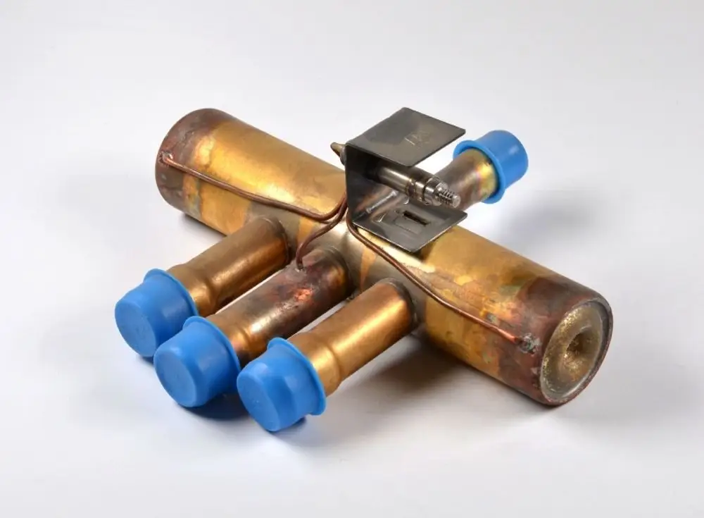 Umkehrventil von Remko mit mehreren Anschlussleitungen und Schutzkappen in blau. Das Produkt zeigt ein kupferfarbenes Metallgehäuse mit einer fixierten Halterung.
