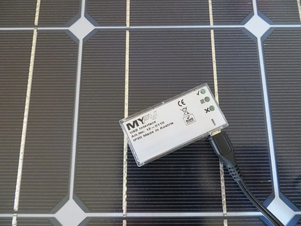 Temperatursensor von MYPV, verbunden über USB, montiert auf einer Sonnenkollektoreinheit. Das Gerät ist auf einem dunkelgrauen Hintergrund platziert.