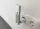 WiFi Stick von Technaxx, in eine Steckdose gesteckt. Graues Gehäuse mit Aufkleber und QR-Code, montiert an einer weißen Wand.