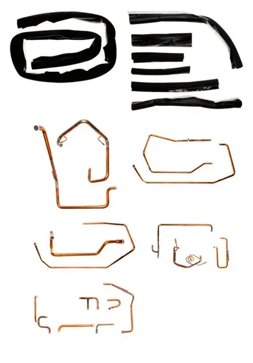 Zwei Gruppen von Kupferrohren in verschiedenen Formen, eine Sammlung schwarzer Kunststoffummantelungen, möglicherweise Zubehörteile für ein Brötje Produkt.