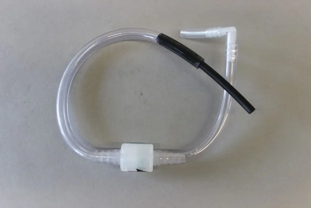 Transparenter Schlauch mit Anschlussstücken, verwendet in Heizungsanlagen, möglicherweise von der Marke Brötje, auf grauem Hintergrund.