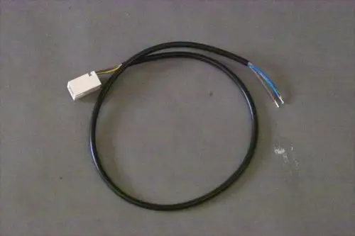 Schwarzes Kabel mit einem weißen Stecker auf einer grauen Unterlage, das zum Anschluss von Brötje-Pumpen verwendet wird. Zwei freiliegende Drähte sind sichtbar.