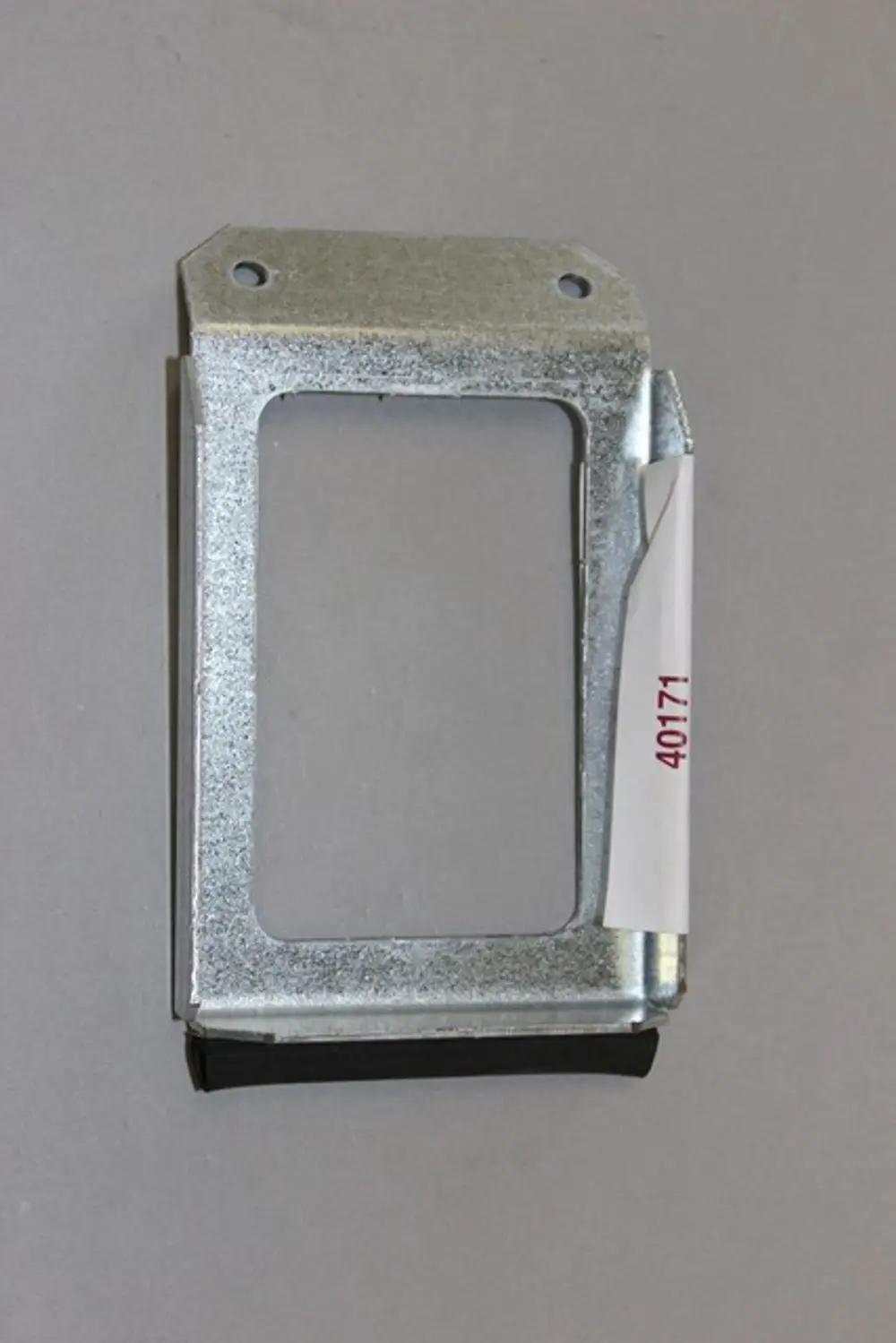 Metallrahmen mit einer offenen Aussparung und Befestigungslöchern. An einer Seite befindet sich ein schwarzes Gummipolster. Produkt von Brötje zur Anwendung im Heizungsbereich.