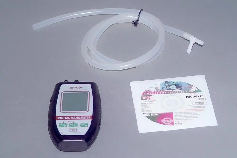 Digitalmanometer von Brötje mit zugehörigem Schlauch und CD. Gerät zur Druckmessung, abgebildet auf grauem Hintergrund.