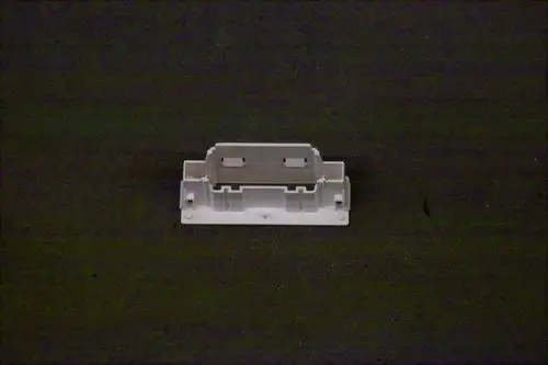 Weißes Kunststoffteil, das möglicherweise eine Magnetspule oder Halterung darstellt, auf dunklem Hintergrund. Produkthersteller könnte Brötje sein.