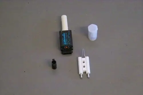 Ein Set bestehend aus mehreren Komponenten, darunter ein schwarzes Bauteil mit Anschluss, ein weißer Stift und ein kleiner schwarzer Zylinder, hergestellt von Brötje.