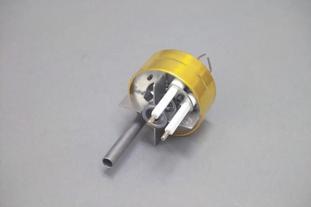 Mischkopf mit runder Metallbasis, zwei weiße Zuleitungen und einem Seitenrohr. Teil eines Heizungssystems, möglicherweise von der Marke Brötje.