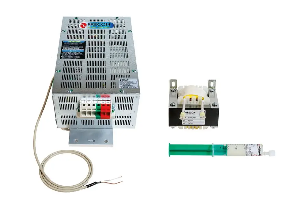 Frequenzumformer von Brötje mit Kühlrippen und Anschlussklemmen, zusammen mit einem Transformator und einer Spritze. Geräte zur Steuerung von elektrischen Motoren.