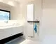 Minimalistisches Badezimmer mit weißem Waschtisch, großem Spiegel und einem weißen Kermi Niva Soft T21 Heizkörper mit dunklem Regal und blauem Handtuch.