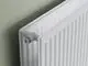 Nahaufnahme eines weißen Kermi Therm-x2 Heizkörpers vor einer hellgrünen Wand.