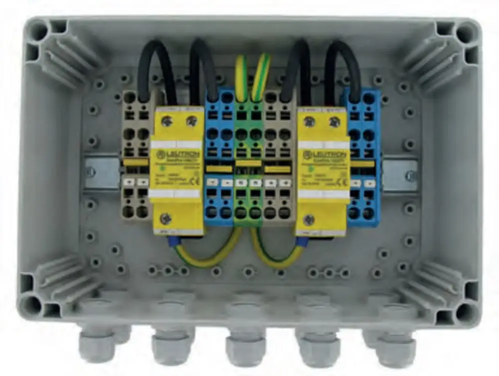 Verteilerbox mit mehreren Klemmen, in der leutron-Komponenten installiert sind. Kabelanschlüsse sind vorhanden, montiert in einem grauen Gehäuse.